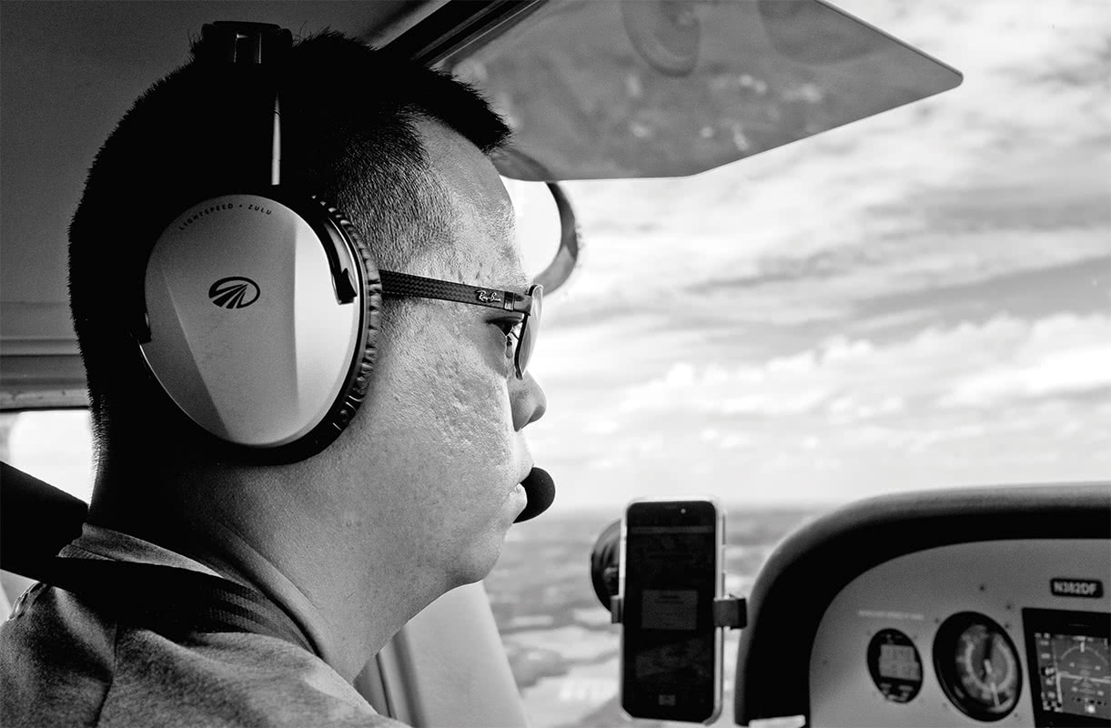 Black and white photo of a pilot in the flight deck of a small plane