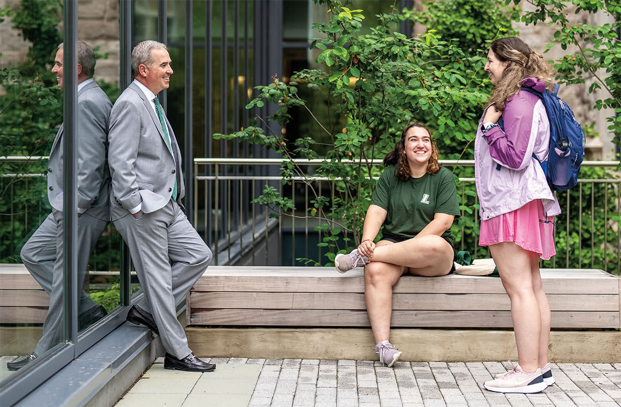 President Terry Sawyer talks with two students outside on a sunny day