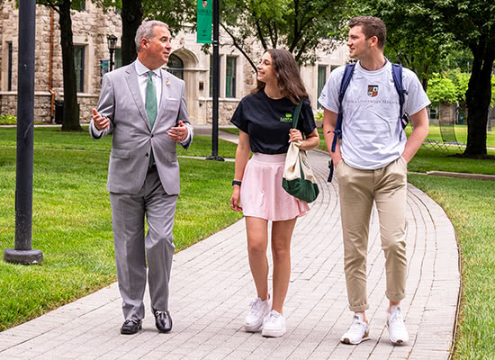 President Terry Sawyers walks down the quad of Loyola's Evergreen campus with two students