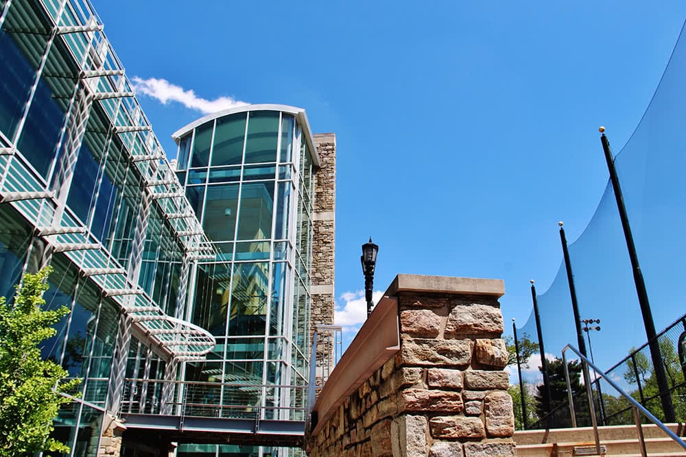 The tall glass windows of the student center in front of a blue sky