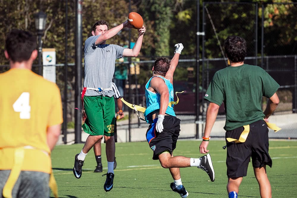 A student leaps to catch a football  during a flag football game