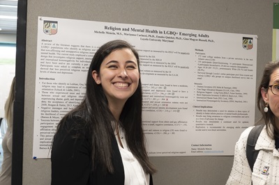 Graduate student smiling in front of research poster