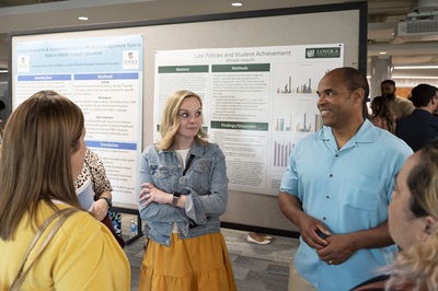 Presenters smile in front of poster at Emerging Scholars Loyola University Maryland