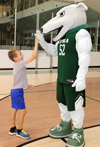 A young child high fives Loyola's greyhound mascot