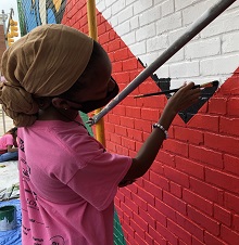 A young woman paints a part of the mural