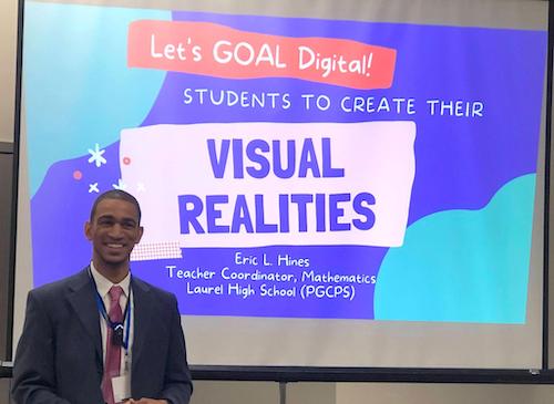 man in sut standing in front of a presentation screen that says: Let's GOAL Digital! Students to create their visual realities