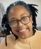 Head shot of Black woman with glasses and yellow sweater