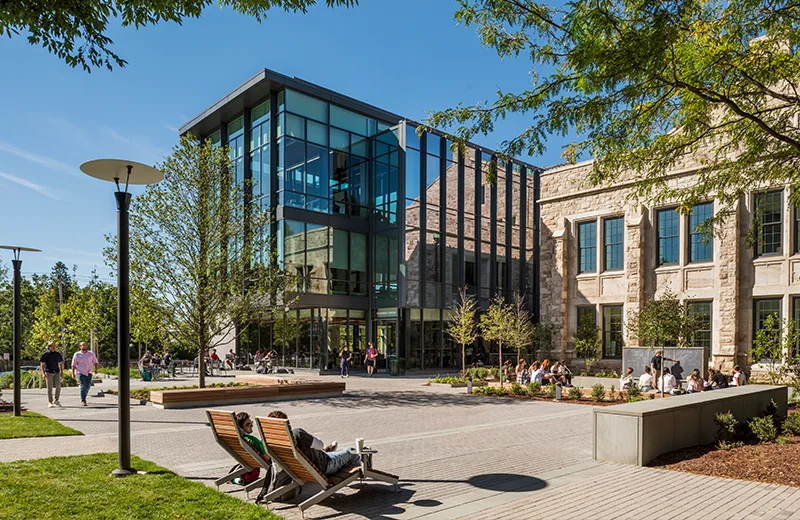 Exterior photo of the Fernandez building, with students sitting in chairs and having an outdoor class