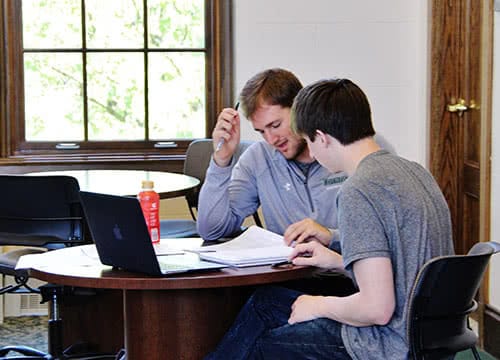 Two students working together a table in the Study