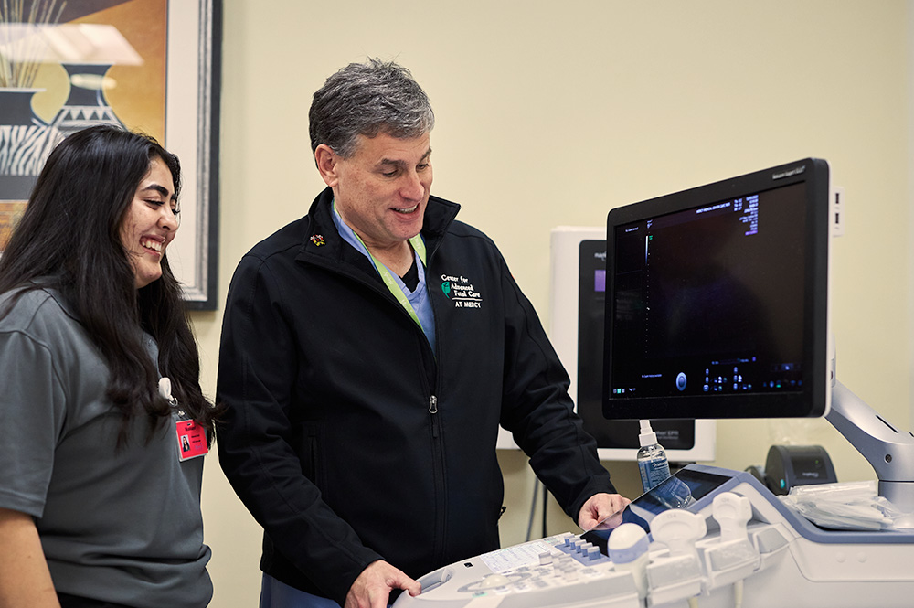 A nurse and a student working on an ultrasound machine