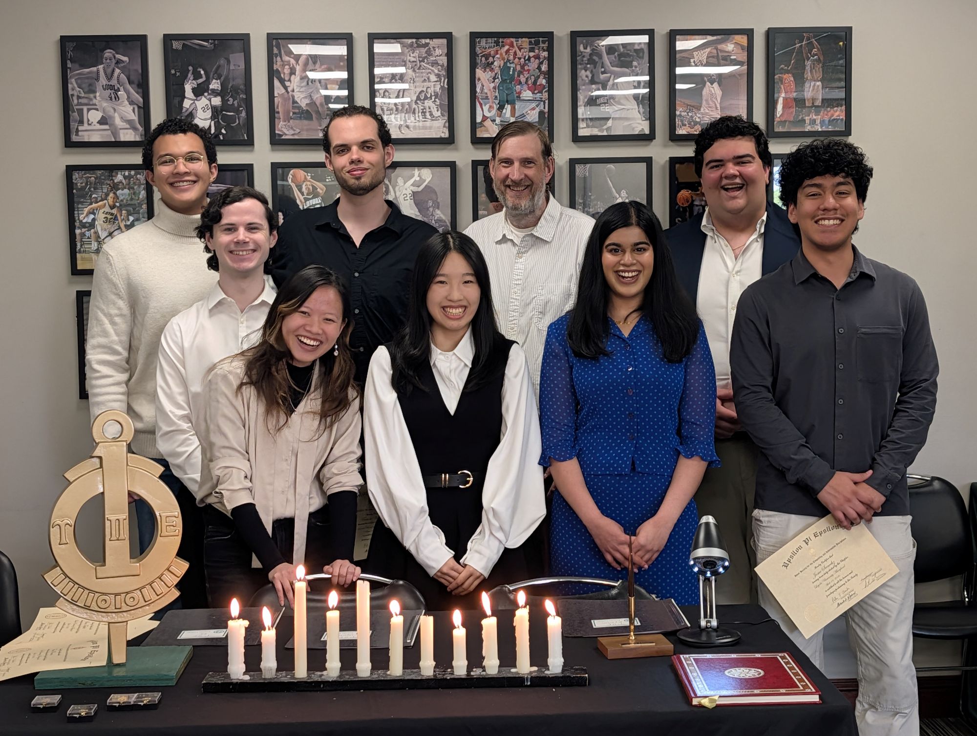 Students in an honor society pose together with lit candles.