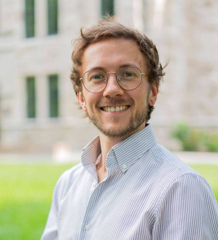 Rhys Williams stands in a dress shirt and glasses on Loyola