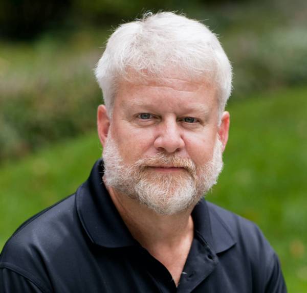 David Rivers headshot in navy polo and grassy background