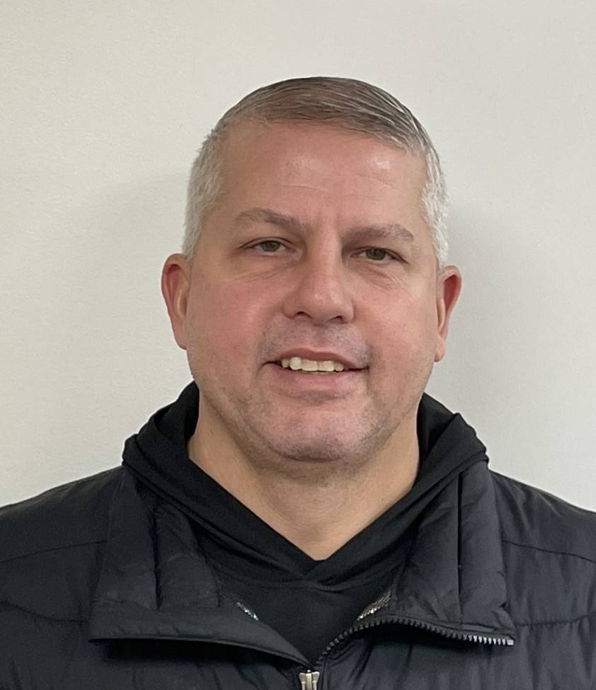 Wade Zufall headshot with black hoodie and vest on white background
