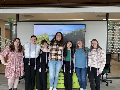 2024 Tri Iota Inductees standing in a line with lilac cords aournd their necks