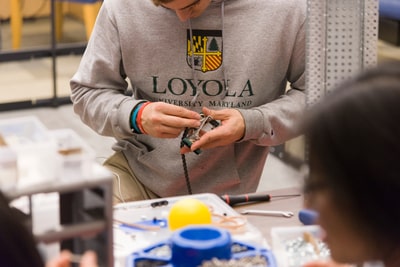 Student tinkering with small metal robotics parts at a work bench