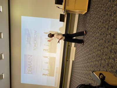 Professor Kelly Keenan gesturing to two movie posters projected on a large screen