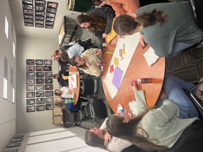 students sitting around a round table with colorful craft supplies