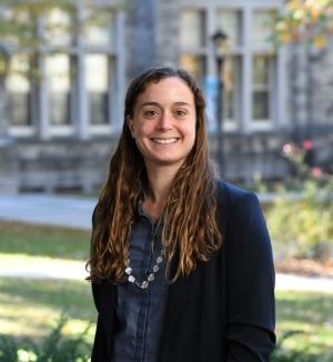 Heidi Shaker smiling standing outside with a stone building in the backgrouns