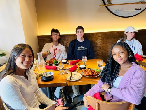 college students sitting around a table with food