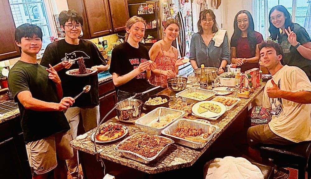 students and faculty posing around a table full of food