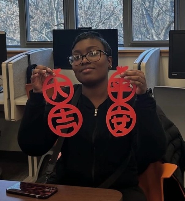 Student posing with red paper craft
