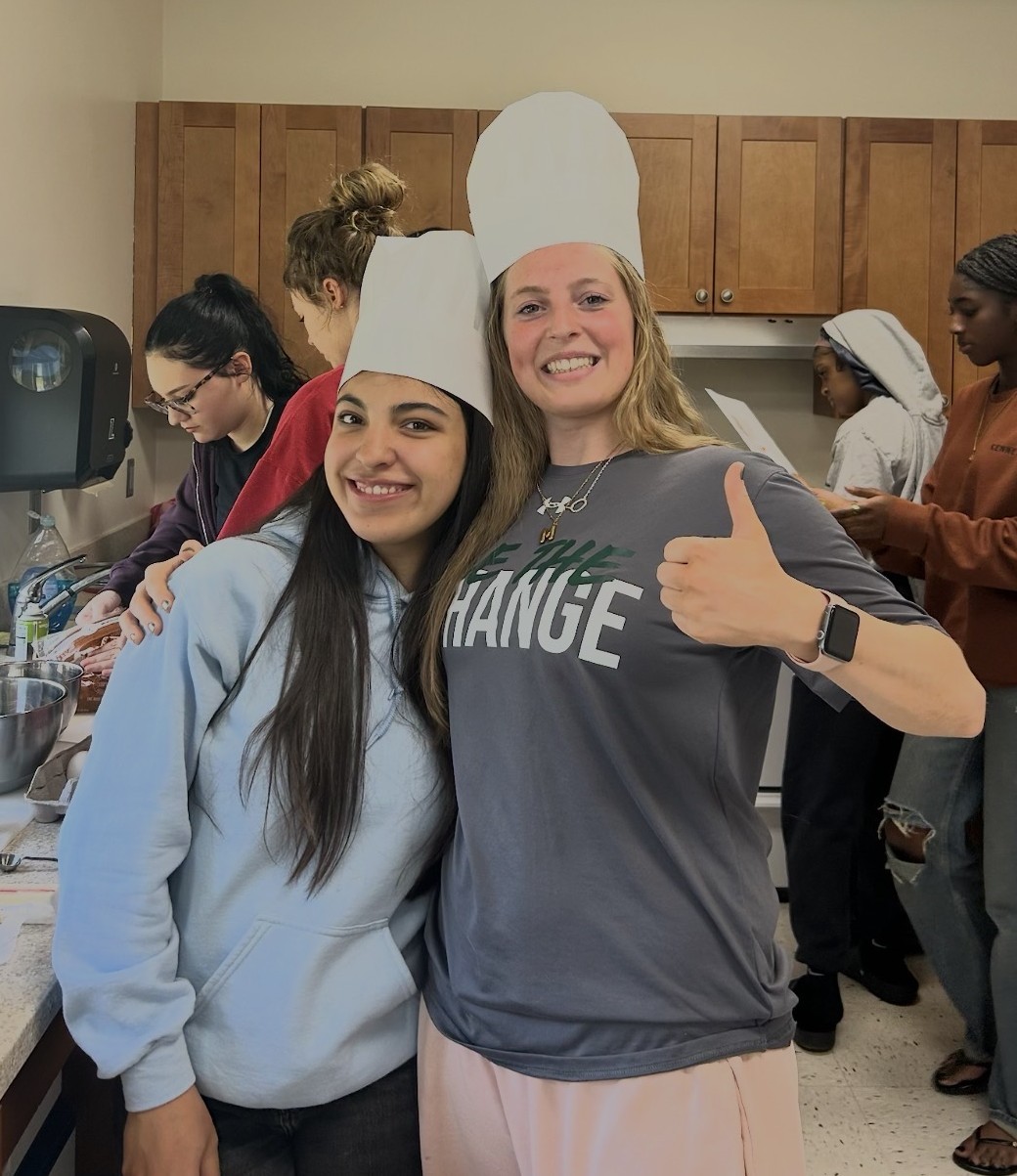 students posing and smiling with white chef hats