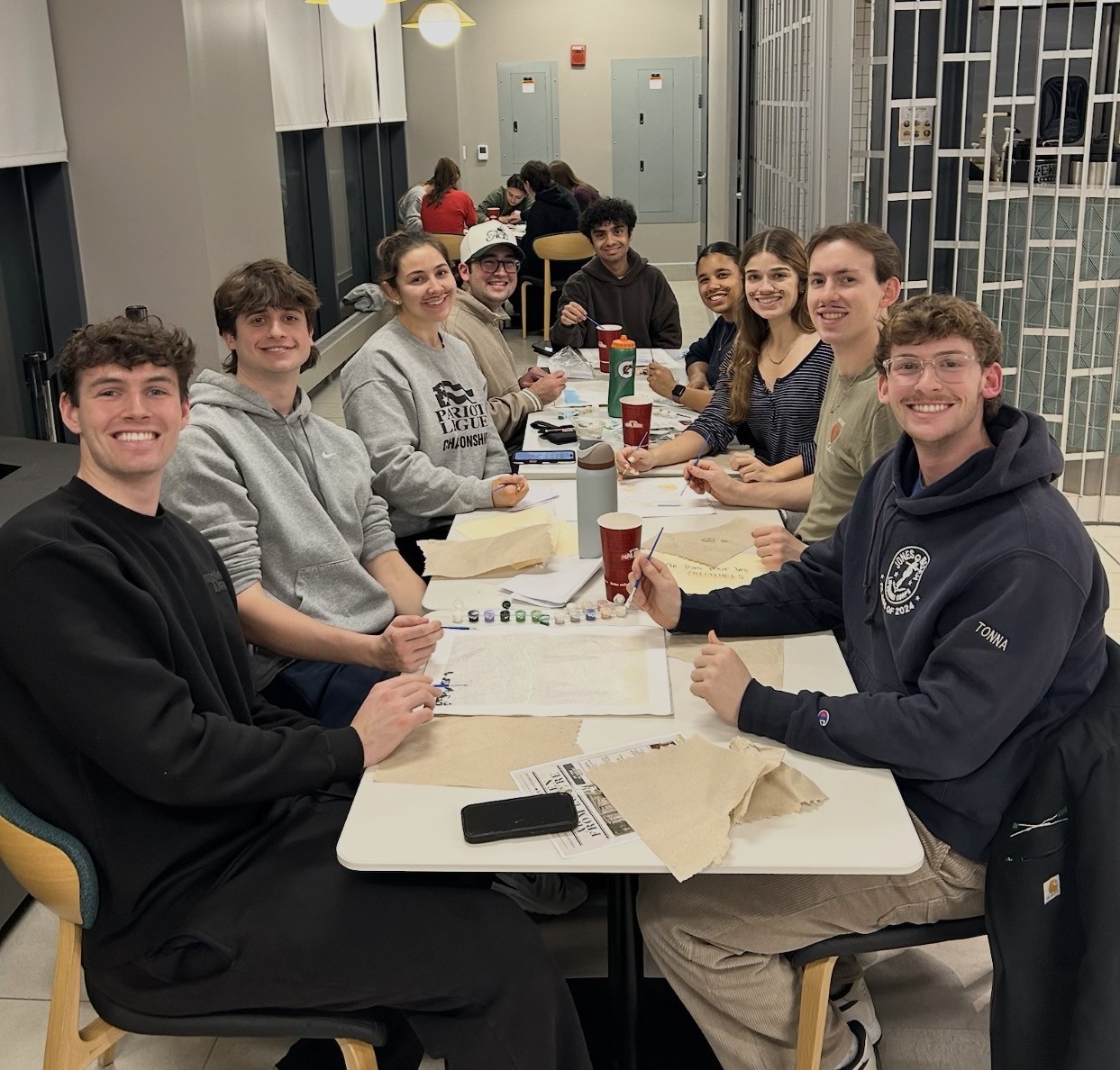 students posing together around table at painting event