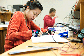 Student working intently on a lab amongst physics lab equipment