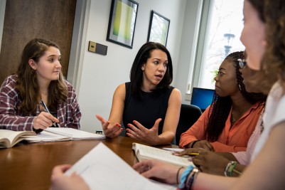 Dr. Heather Lyons having a discussion with students, who are engaged in the conversation and taking notes.