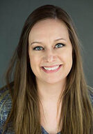 Dr. Emalee Quickel smiling warmly at the camera in front of a dark grey background