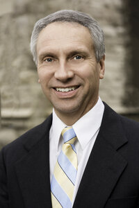 Jeff Lating, smiling in front of a stone wall