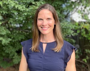 Dr. Brianne Higgins Roos in blue top in front of shrubbery