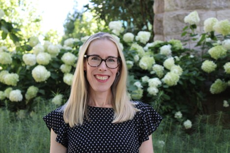 Kim Sharpley in polka dot top in front of flowers