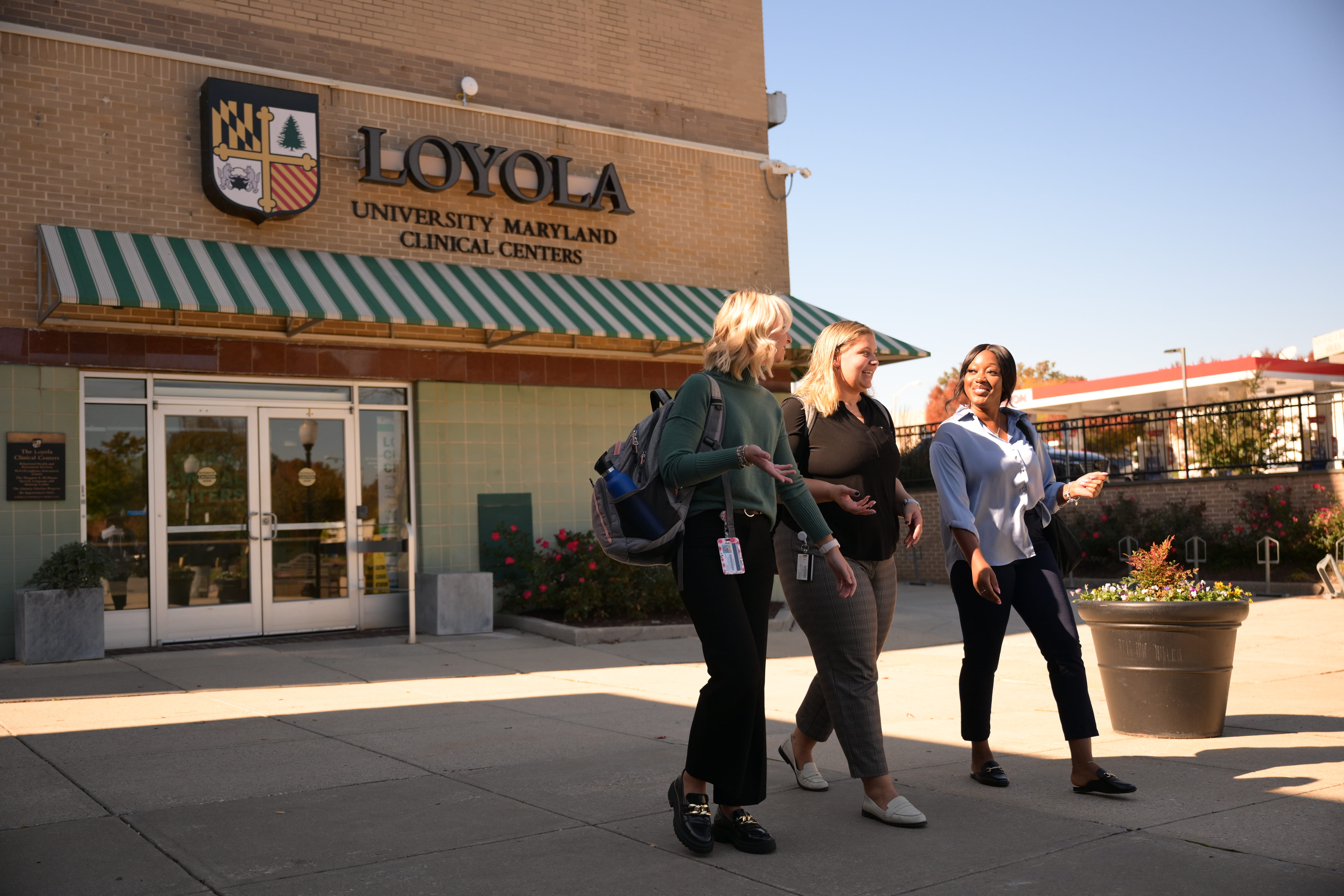 Three students walk away from the main entrance of the Loyola Clinical Centers.