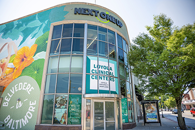 The corner of the Loyola Clinical Centers building, with large glass windows and a colorful mural of flowers and birds.
