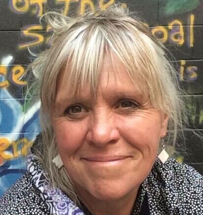 Headshot of Mary Beth Akre with a spray-painted wall in the background
