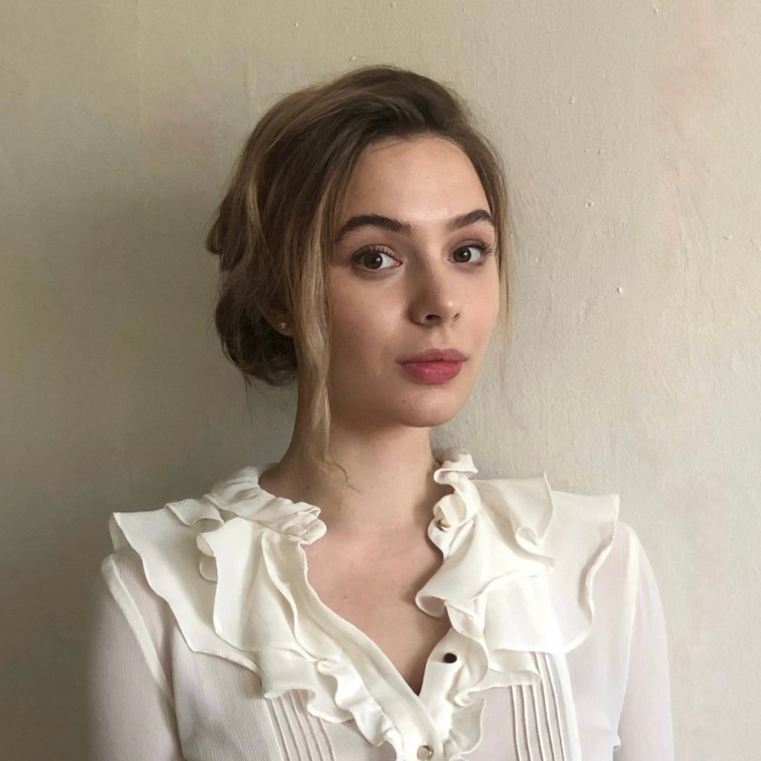 Headshot of Mariia Usova wearing a white ruffled shirt
