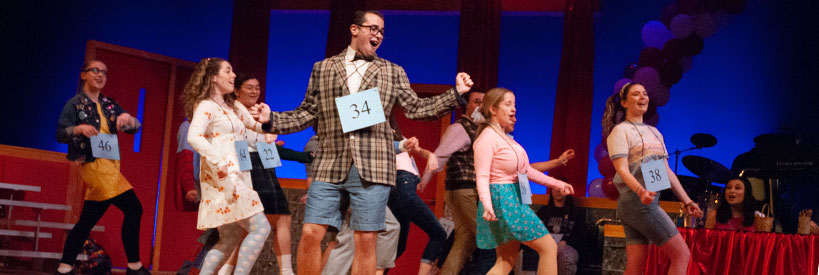 Loyola students performing a number as dancing, singing, elementary-aged spelling bee competitors 