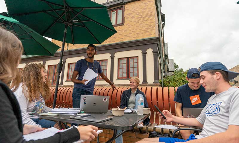 students gather together for a group project outside the humanities building 