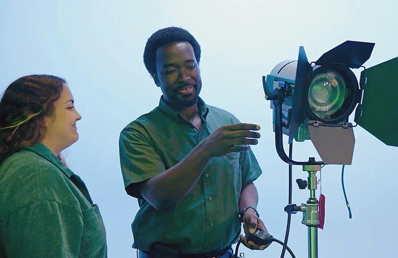 A student and professor setting up a studio light