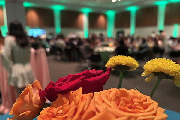 A centerpiece floral arrangement frames a view of McGuire Hall during the 2025 Senior BBQ
