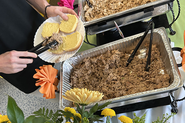 A senior fills their plate with barbecued pulled pork at Loyola's 2025 Senior Barbecue