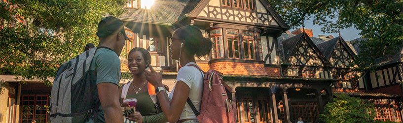 Three Loyola students smiling and talking in front of the Humanities building