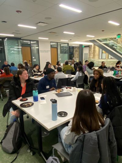 A packed table with students chatting and enjoying treats.