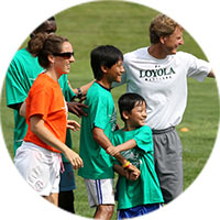 Children and adults on a grassy field smile