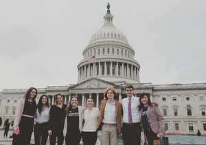 eight people standing in front of US capitol building.