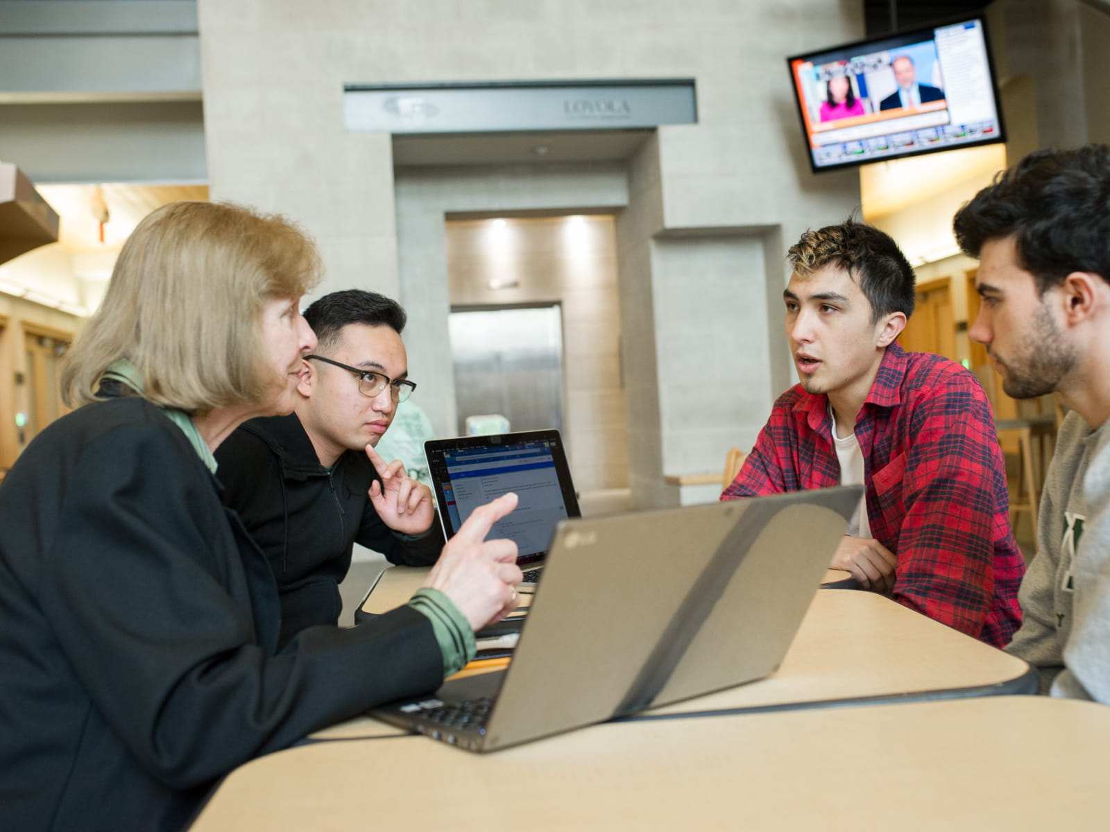 Three students and a Coach having a discussion in a classroom