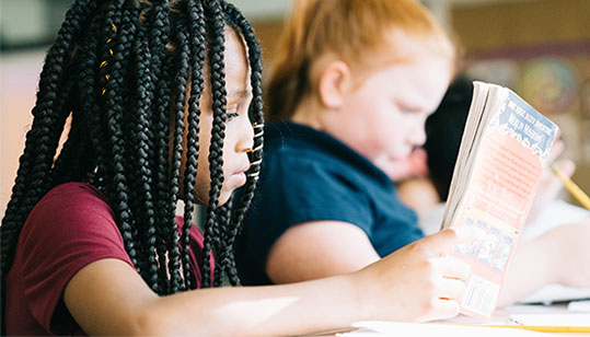 Two student at their desks reading books