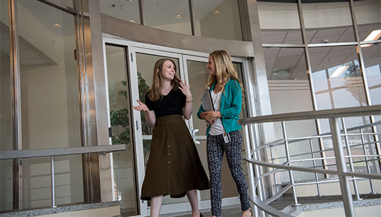 Two leaders in education having a conversation while walking down some stairs